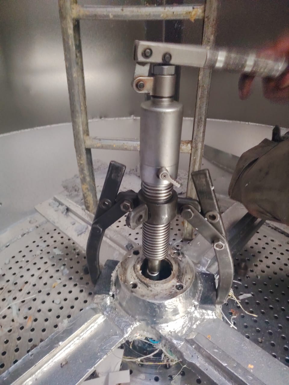 Hydraulic bearing puller fitted over a shaft inside a stainless vessel