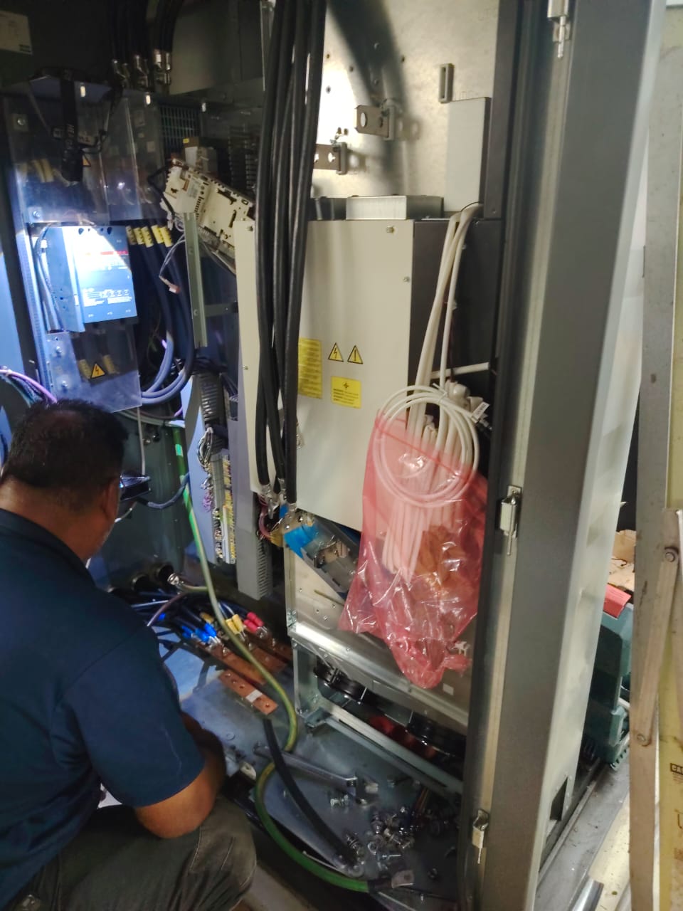 Technician wiring inside an open industrial drive cabinet