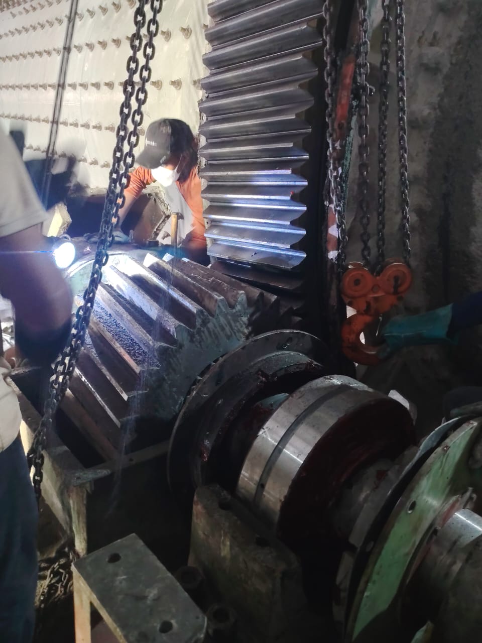Large helical gear suspended on chains during an overhaul