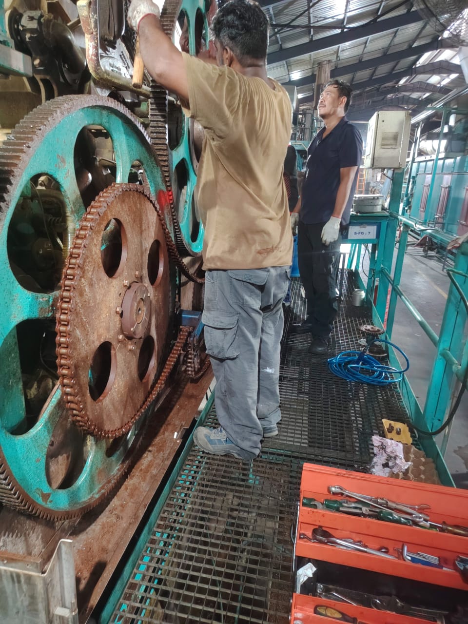 Technicians working on a large geared drive from a steel platform