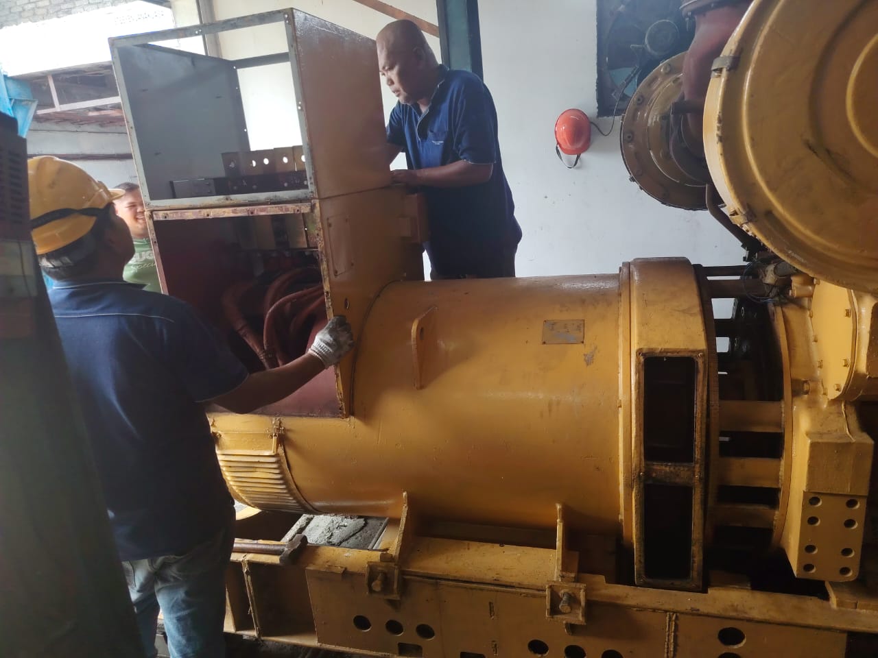 Technicians servicing a large yellow generator set