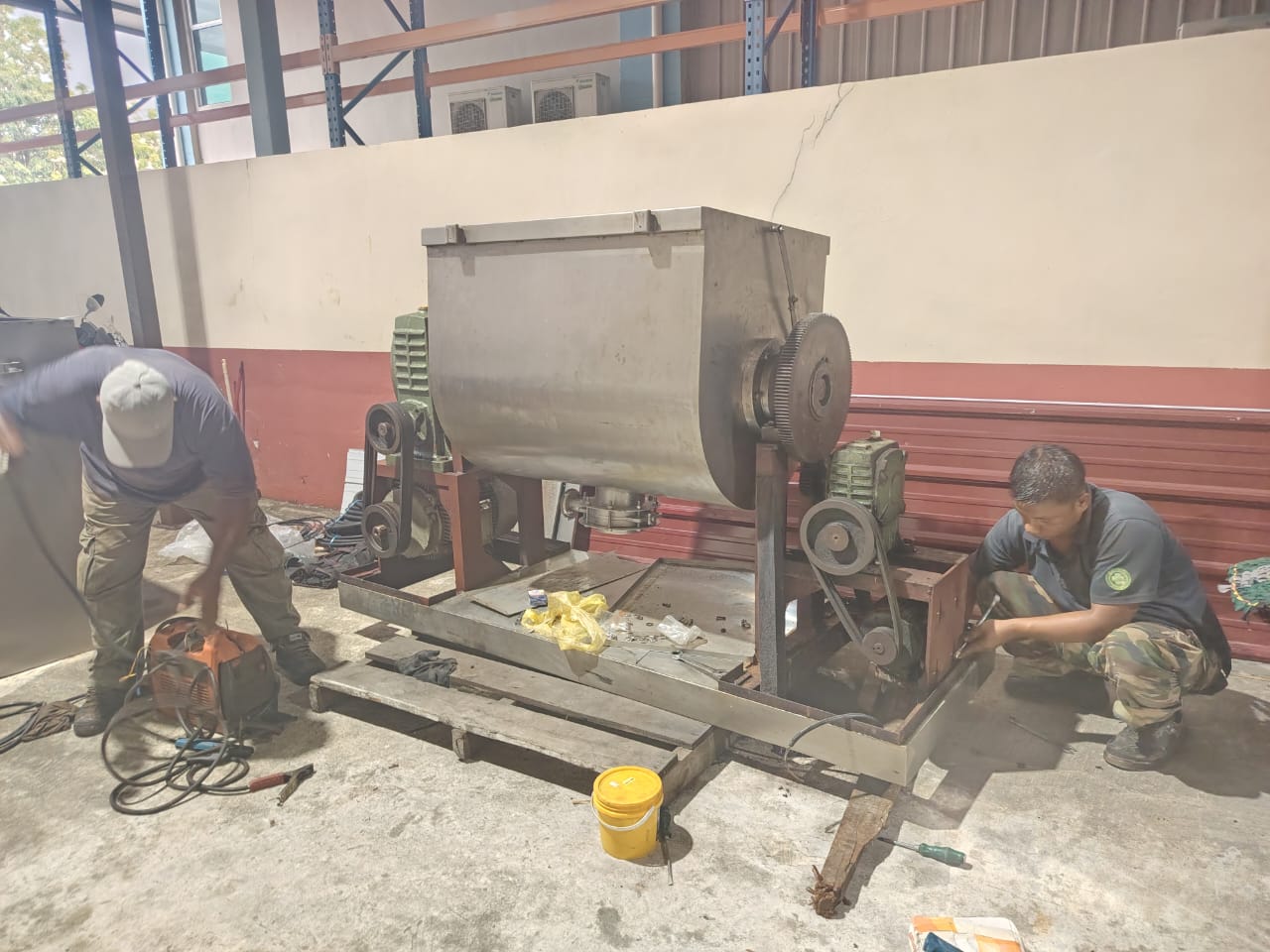 Technicians welding and fitting drives on a stainless ribbon mixer